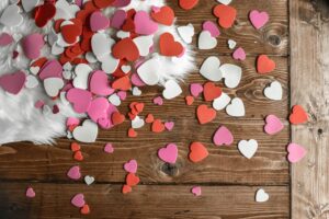Pink, red, and white hearts scattered on a wooden background