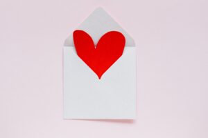 red heart in a white envelope on a pink background