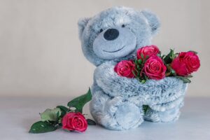 Grey stuffed bear holding pink roses